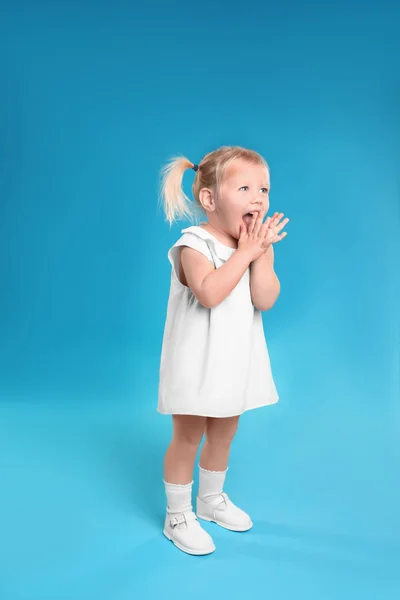 Милая маленькая девочка позирует на светло-голубом фоне — стоковое фото