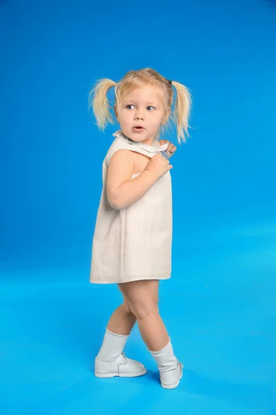 Мила маленька дівчинка позує на світло-блакитному тлі — стокове фото