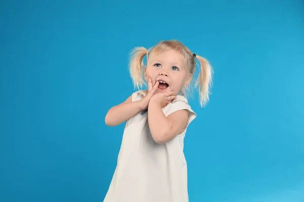 Schattig klein meisje poseren op licht blauwe achtergrond — Stockfoto