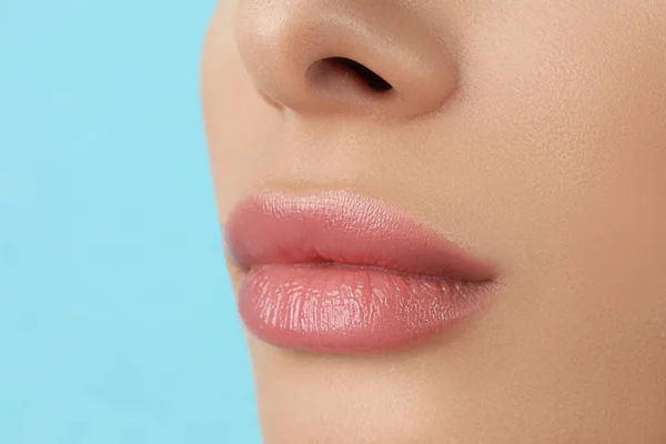 Woman with beautiful full lips on light blue background, closeup — Stock Photo, Image