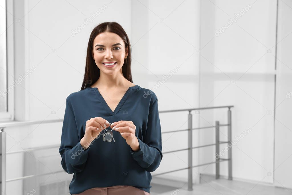 Female real estate agent holding key in new apartment