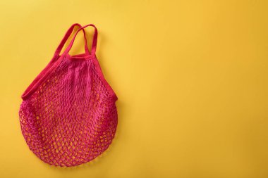 Sarı arka planda boş pembe ağ torbası, üst manzara. Tex için boşluk