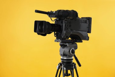 Sarı arka planda modern profesyonel video kamera