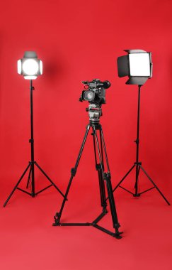 Kırmızı arkaplanda profesyonel video kamera ve ışıklandırma ekipmanları