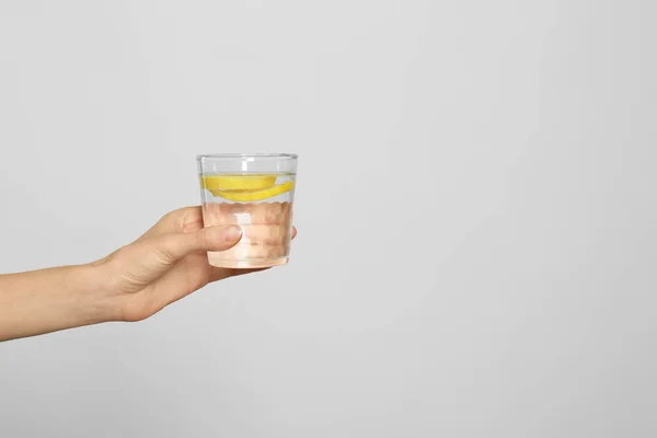 Mujer joven con vaso de agua de limón sobre fondo claro, cerca —  Fotos de Stock