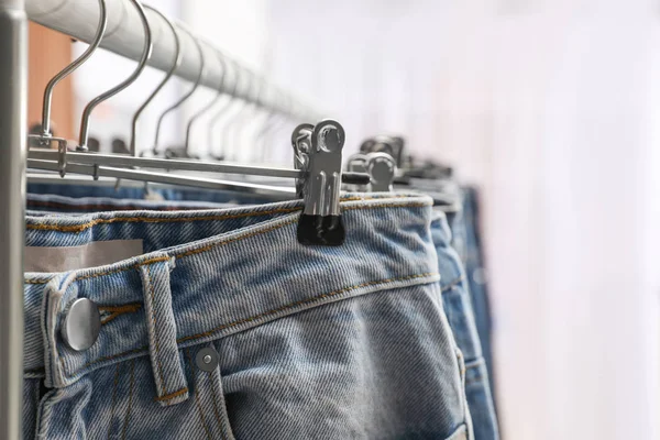 Rack with different jeans indoors, closeup view — 스톡 사진