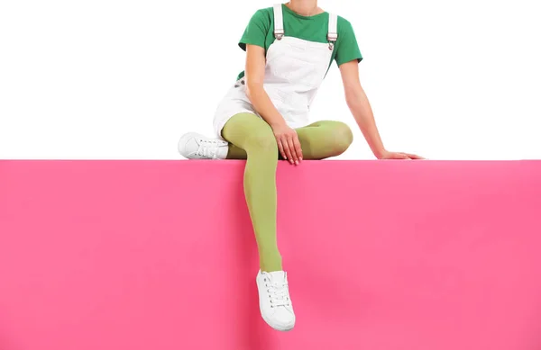 Woman wearing green tights and stylish shoes sitting on color ba — 스톡 사진