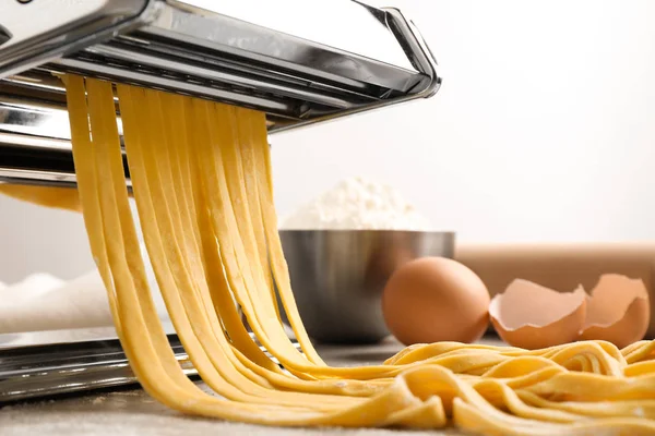 Pasta maker machine with dough on grey table, closeup — Stock Photo, Image