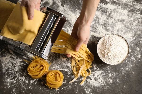 Mujer preparando fideos con máquina de hacer pasta en la mesa gris , — Foto de Stock