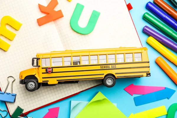 Flat lay composition with yellow school bus model on light blue