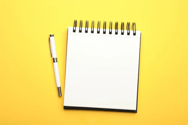 Κομψό ανοιχτό σημειωματάριο και στυλό σε κίτρινο φόντο, πάνω όψη — Φωτογραφία Αρχείου