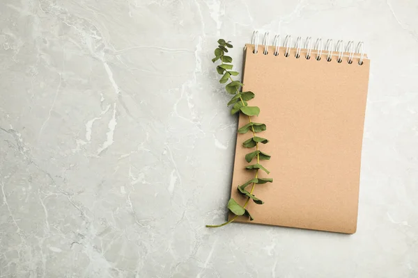 Notebook elegante e eucalipto na mesa de mármore, vista superior. Espaço — Fotografia de Stock