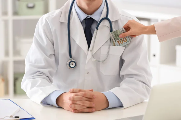 Patient putting bribe into doctor's pocket in clinic, closeup. C — 스톡 사진