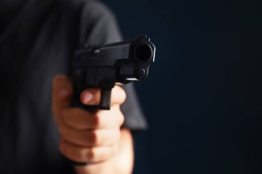 Karanlık arka planda silah tutan adam, yakın plan.