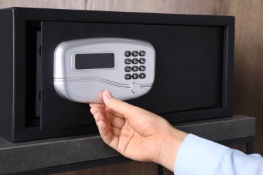 Kadın elektronik kilitle siyah çelik kasa açıyor, yakın plan.