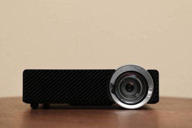 Bej arkaplana karşı ahşap masa üzerinde modern video projektörü
