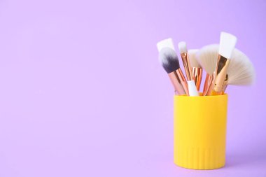 Eflatun arkaplanda bulunan profesyonel makyaj fırçaları