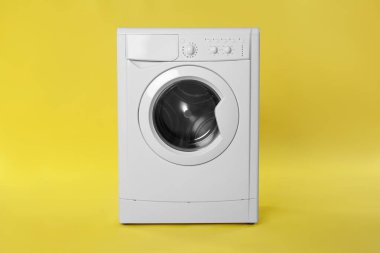 Sarı arka planda modern çamaşır makinesi. Çamaşır günü