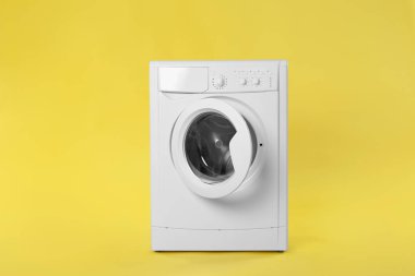 Sarı arka planda modern çamaşır makinesi. Çamaşır günü
