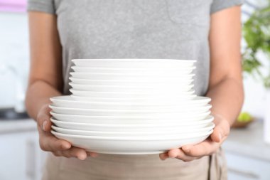 Mutfakta temiz beyaz tabakları tutan kadın, yakın plan.