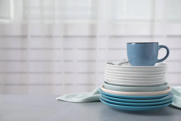 Set of clean tableware on light grey table. Space for text — ストック写真