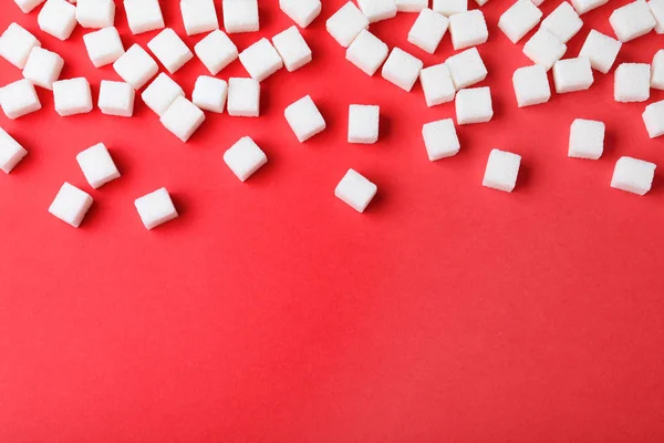Cubos de azúcar refinados sobre fondo rojo, vista superior. Espacio para texto — Foto de Stock