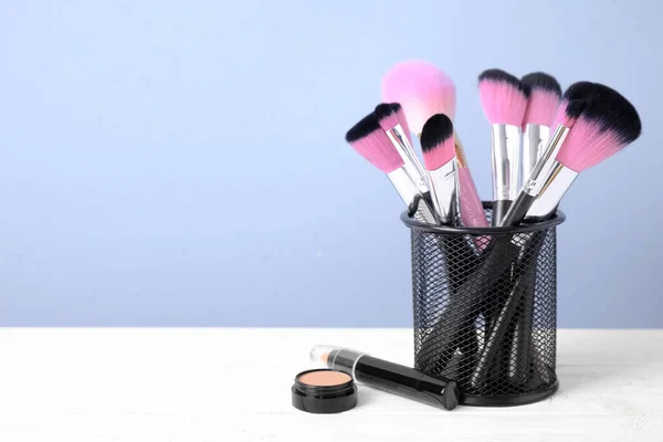 Set of professional makeup brushes in holder on white wooden tab — ストック写真