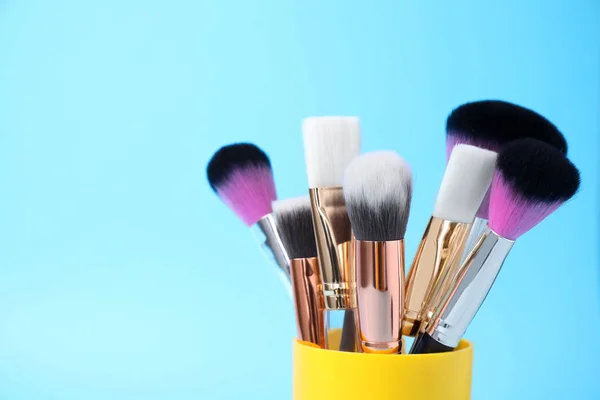 Set de pinceaux de maquillage professionnels en support sur fond bleu clair — Photo