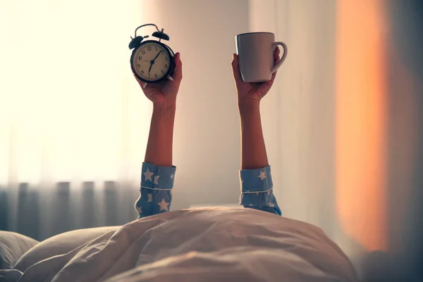 カップと目覚まし時計を持つ女性のベッドの上で クローズアップ横たわっ 朝の時間 — ストック写真