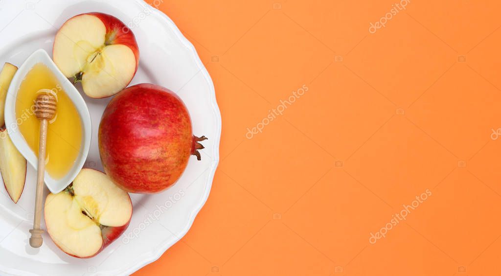 Honey, apples and pomegranate on orange background, top view. with space for text Rosh Hashanah holiday