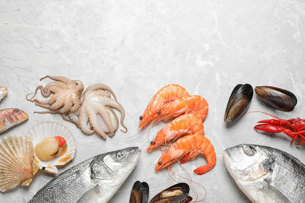 Fresh fish and seafood on marble table, flat lay. Space for text