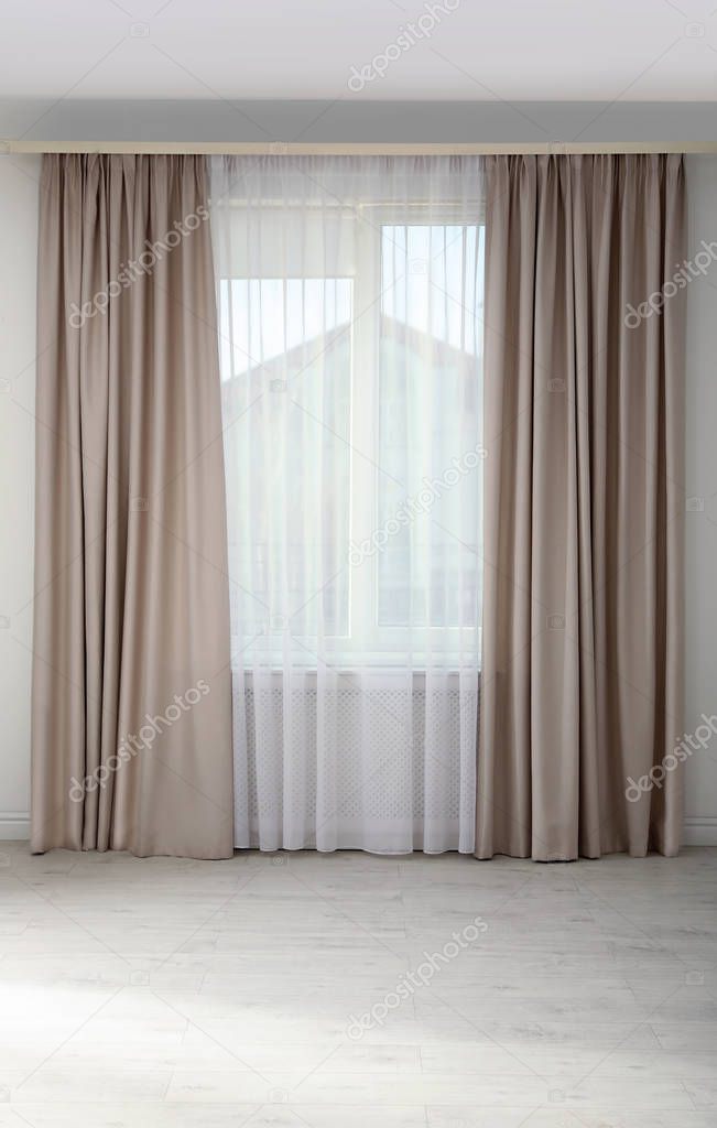 Window with elegant curtains in empty room