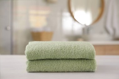 Banyodaki beyaz ahşap masada temiz havlular yığını.