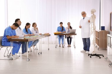 Tıp öğrencileri ve profesör sınıfta insan iskeleti anatomisi okuyor.