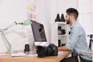 Professional photographer working at table in office, focus on c