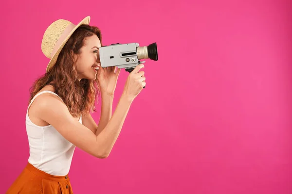 Belle jeune femme utilisant une caméra vidéo vintage sur fond cramoisi — Photo