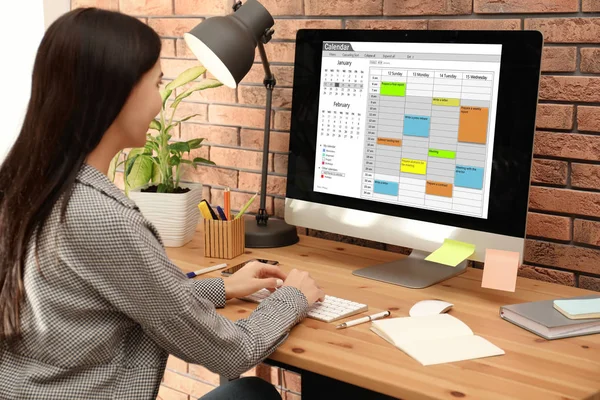 Jovem mulher usando aplicativo de calendário no computador no escritório — Fotografia de Stock