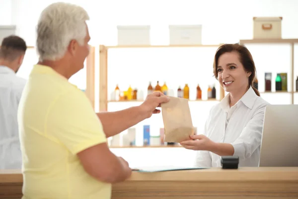 Фармацевт дает лекарства клиенту в аптеке — стоковое фото