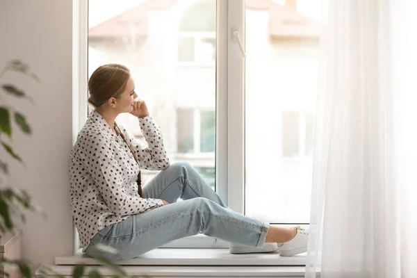 Красивая молодая женщина смотрит в окно дома — стоковое фото