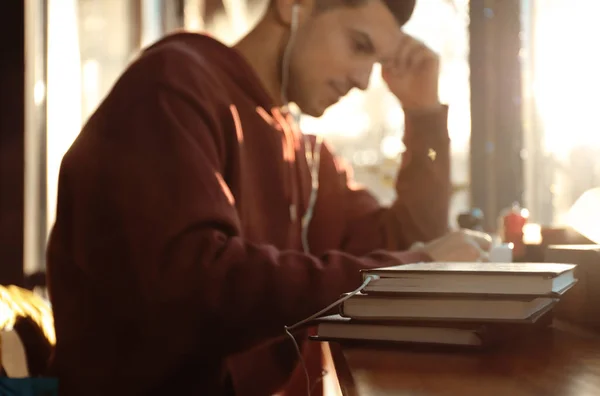 Man met koptelefoon aangesloten om te boeken aan tafel in cafe — Stockfoto