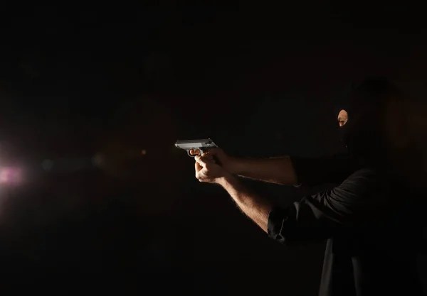 Professionell mördare med pistol på svart bakgrund — Stockfoto