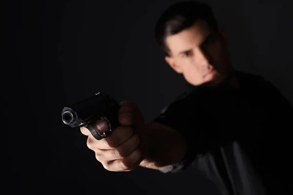 Professional killer on black background, focus on gun — Stock Photo, Image