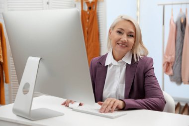 Butikte bilgisayarla çalışan bir kadın işyeri sahibi.