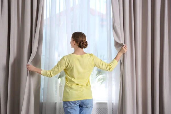 朝家で窓のカーテンを開ける女 — ストック写真