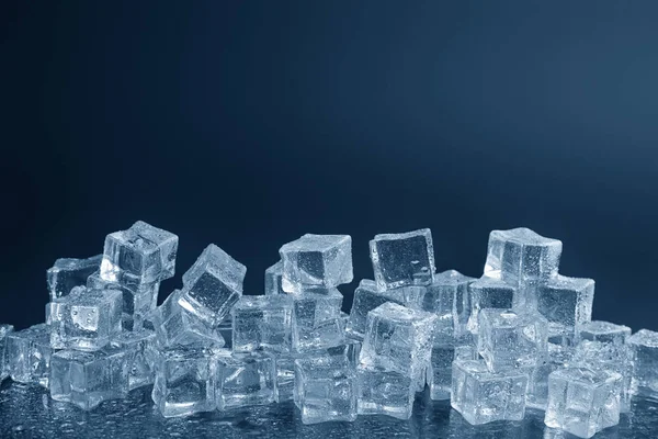 Crystal clear ice cubes with water drops against black background