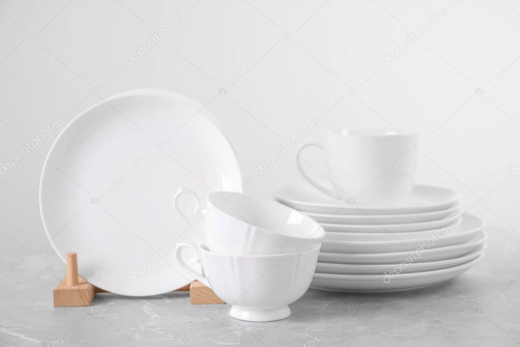 Set of clean tableware on light grey marble table