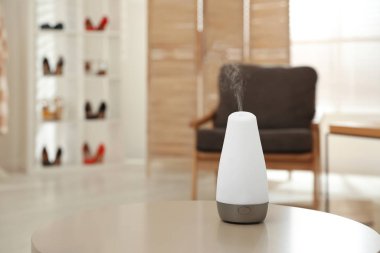 Aroma oil diffuser on table indoors, space for text. Air freshener