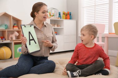 Konuşma terapisti ofiste küçük bir çocukla çalışıyor.