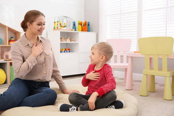 Speech therapist working with little boy in office