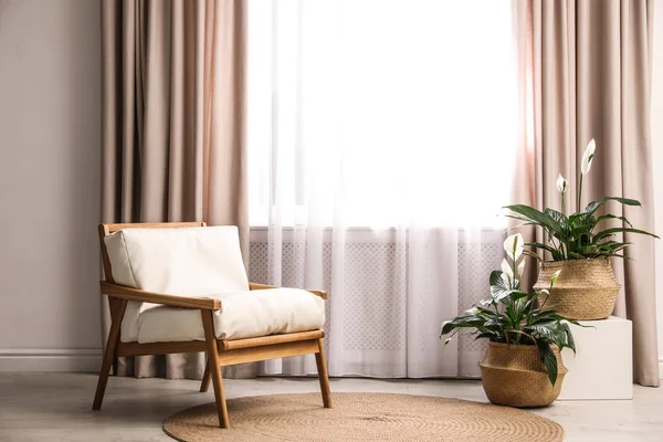 Comfortabele fauteuil bij het raam met elegante gordijnen in de kamer — Stockfoto